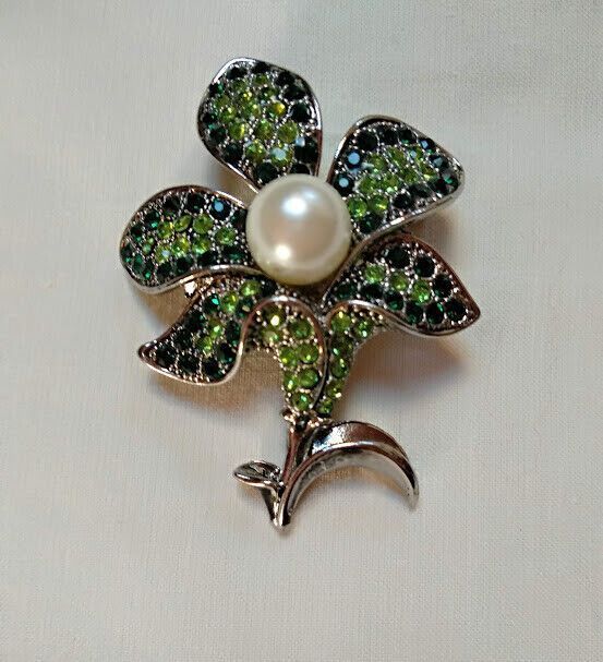 Broche bisuteria plateado en forma de flor cuajado piedras verdes y perla .Nuevo